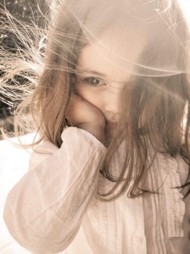 Finalist photo from the 2025 OnePlus Photography Awards showing a young girl with windswept hair and soft sunlight on her face.