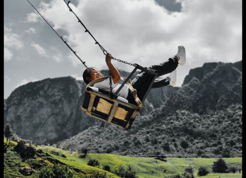Winning photo from the 2025 OnePlus Photography Awards showing a joyful person on a swing against mountain scenery.