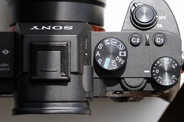 a camera with mode dial set to aperture priority is on a white desk with harsh light