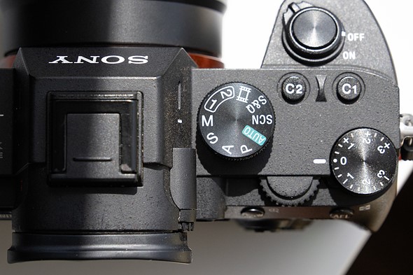 a camera with mode dial set to manual is on a white desk with harsh light