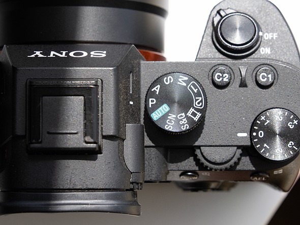 a camera with mode dial set to program is on a white desk with harsh light