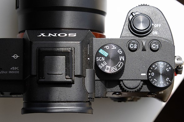 a camera with mode dial set to scene is on a white desk with harsh light