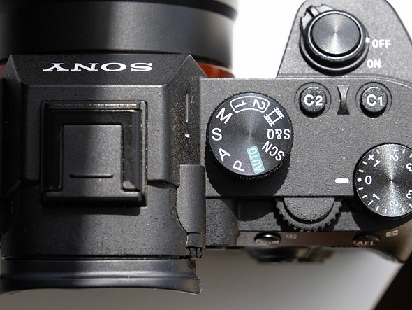 a camera with mode dial set to shutter priority is on a white desk with harsh light