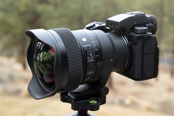 a camera with the Sigma 14mm F1p4 lens is on a tripod in front of a blurrd background