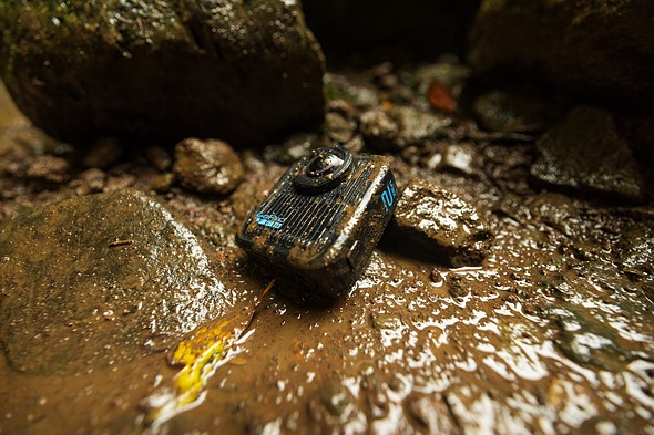 a gopro max2 camera sits covered in mud against rocks