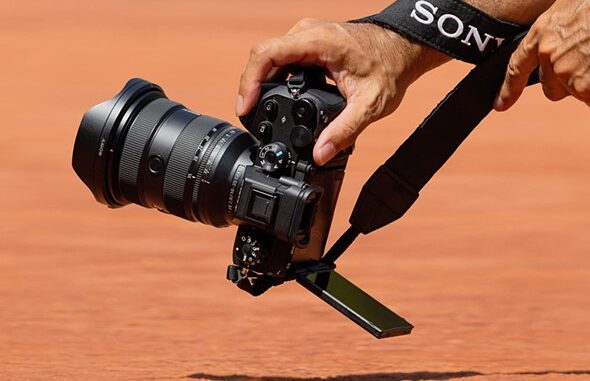 a_hand_holds_a_sony_camera_over_red_dirt