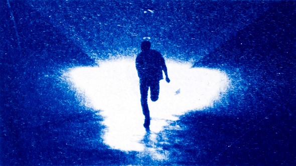 a person runs towards a white light while surrounded by blue