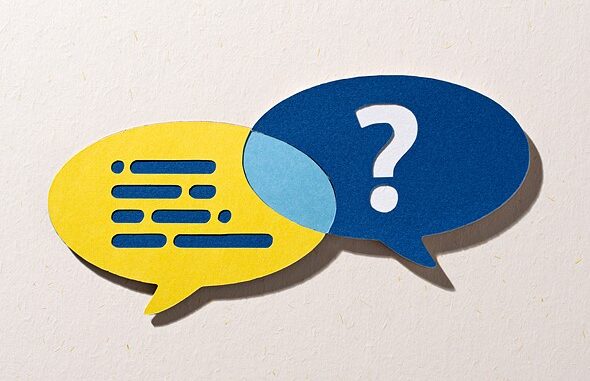 a_yellow_word_bubble_with_blue_lines_overlaps_a_blue_one_with_a_white_question_mark_both_are_placed_on_a_textured_off_white_paper