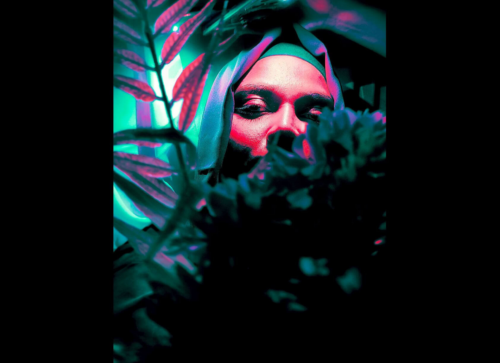 Winning photo from the 2025 OnePlus Photography Awards showing a portrait lit with neon pink and teal light, blending mystery and contrast.