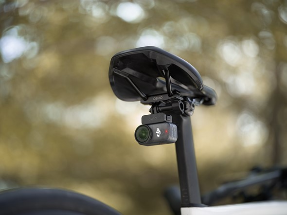 the dji osmo nano is mounted to the underside of a bike seat