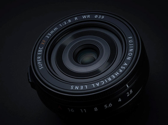 a fujifilm lens is against a black background in dark lighting