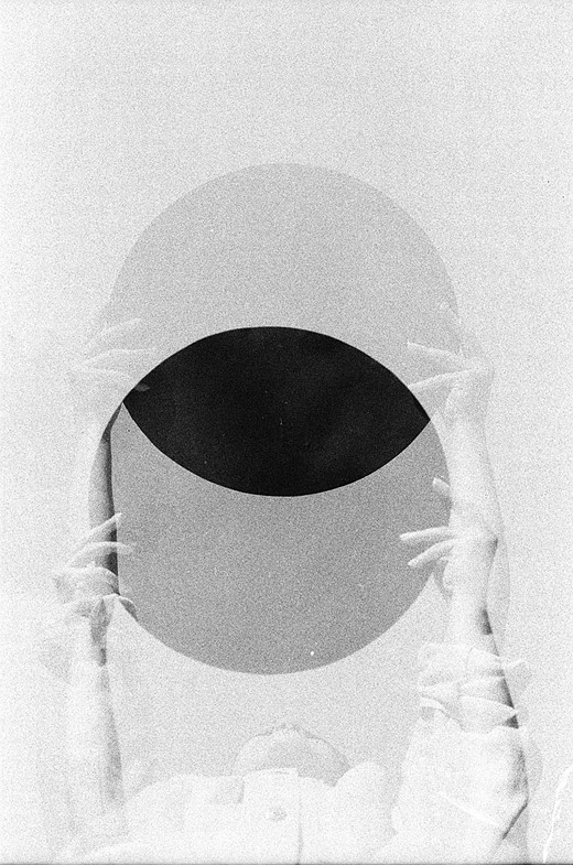 a person holds up a dark circle in front of a dark sky