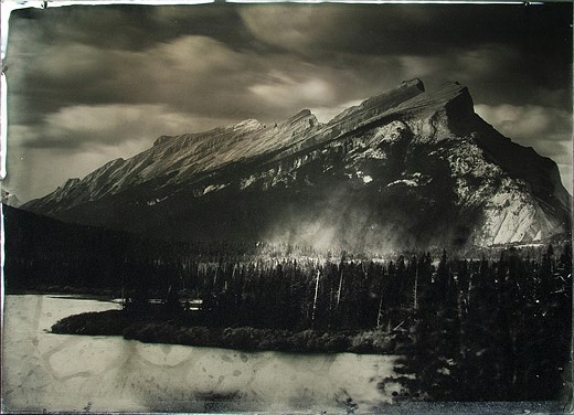 a sharp mountain extends above a lake and forest