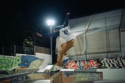 a skateboarder jumps in a skatepark at night