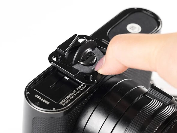 a thumb presses on the peak design field plate on the bottom of a camera