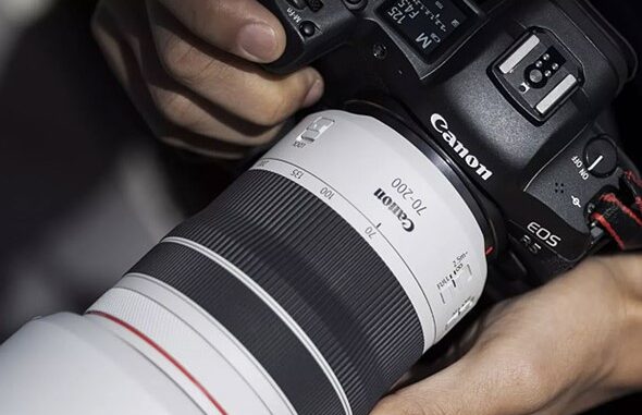 hands_hold_a_canon_camera_with_white_lens_attached