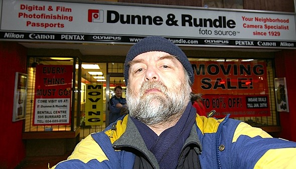 man-standing-outside-dunne-and-rundle-in-vancouver-canada-by-jacksimpson