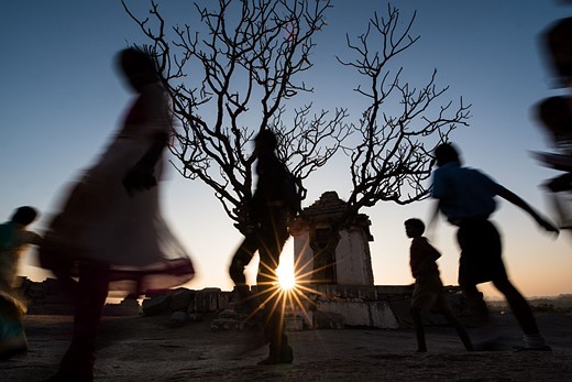 people are blurred while moving in front of a setting sun