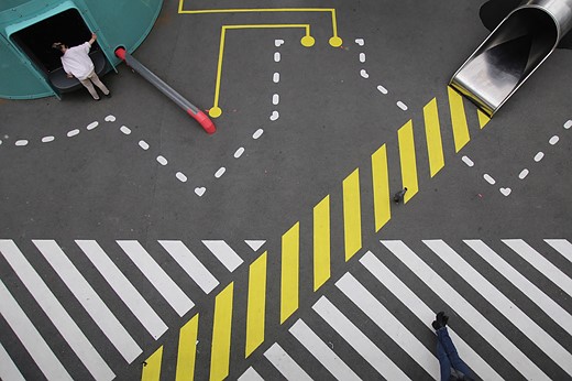 white and yellow lines are painted on the ground woth a person standing at a green structure