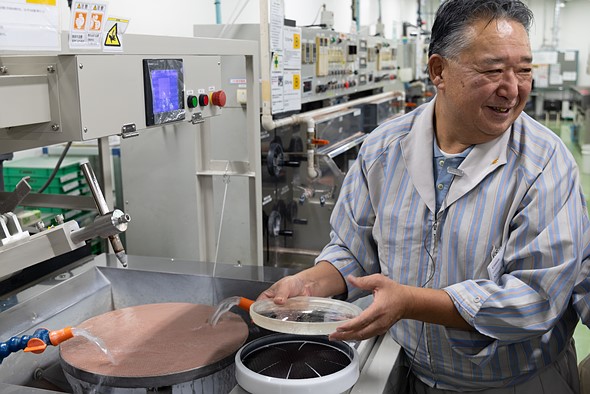 A Canon master-craftsman shows a glass element thats been machine polished