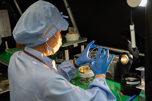 A Canon technician examines a lens element