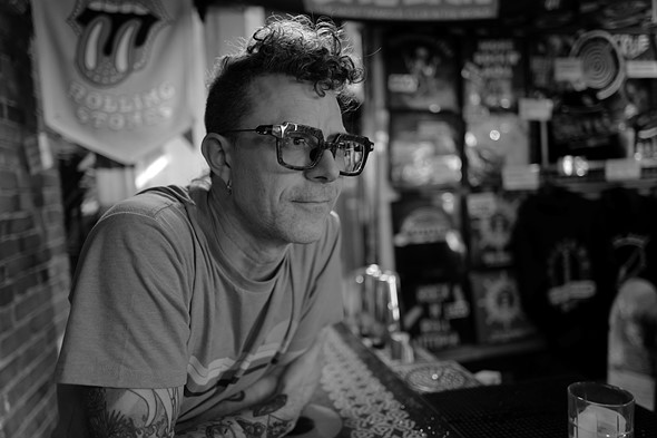 Man wearing glasses leaning across a bar