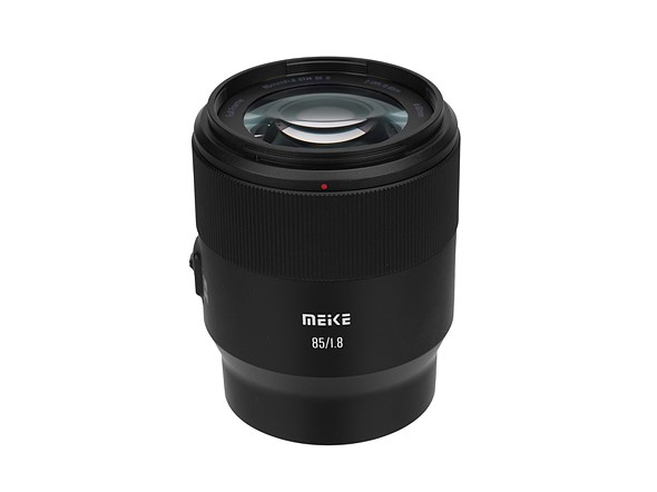 a black meike lens stands on a white background