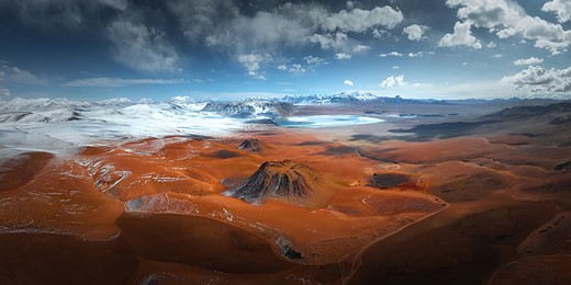 a vast andscape with red hills and snowy mountains in the distance