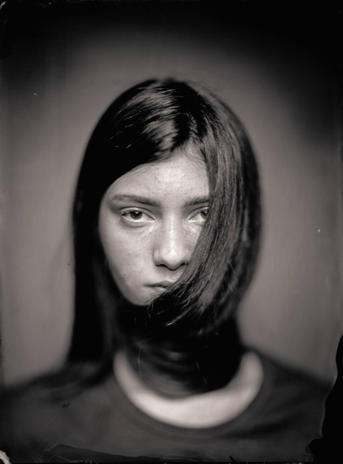 a woman with dark hair stares forward with her hair wrapped around her face