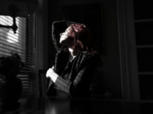 A cinematic portrait of a woman bathed in window light, her face partially illuminated to create mood and contrast.