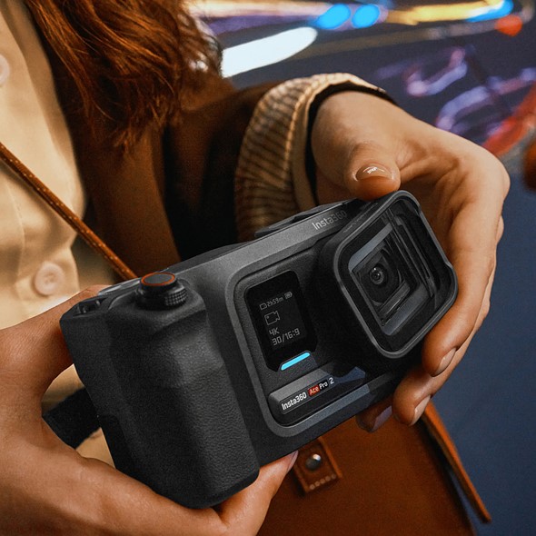 hands hold the insta360 ace pro two while attaching a lens