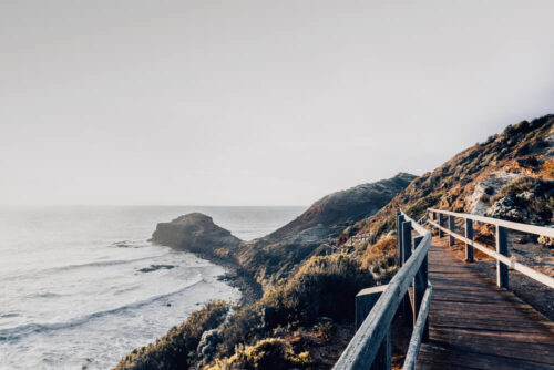 Landscape photo by Graeme Ian Hall featuring a coastal boardwalk overlooking cliffs and the ocean under soft morning light.
