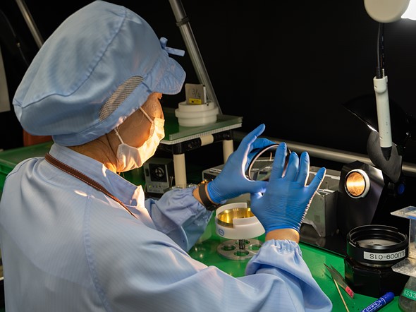 A Canon technician examines a lens element