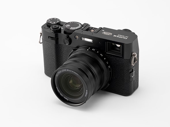 a black viltrox conversion lens is attached to a black fujifilm x100 camera placed on a white table