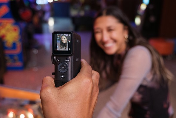a hand holds a camera with small screen while recording a smiling woman