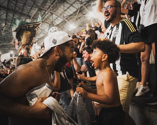 a man leans down to scream with a young boy in a crowded stadium