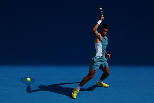 a man swings a tennis racket on a blue court