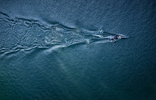 a slim boat cuts through rippled water