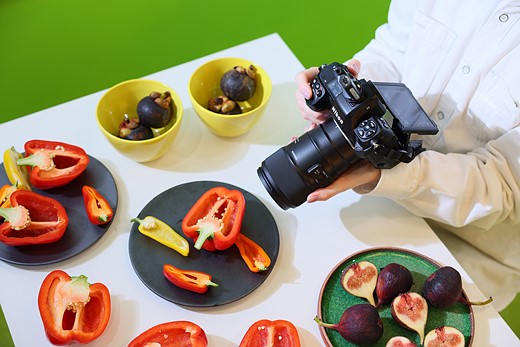 person taking macro shot of a bell pepper on a table covered with plates of food