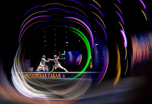 two fencers bout in a Dark room with colorful lights swirling around