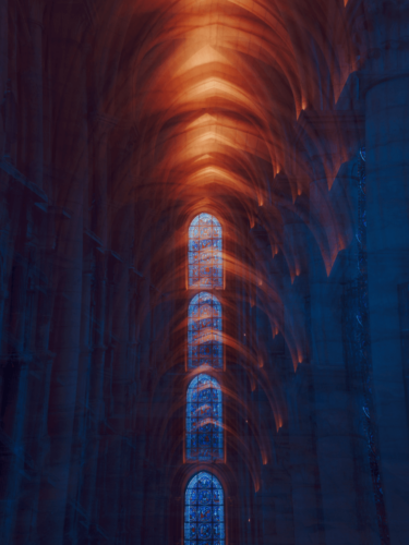 Cathedral interior with glowing stained glass windows framed by repeating arches, illustrating framing techniques that emphasize depth and symmetry.