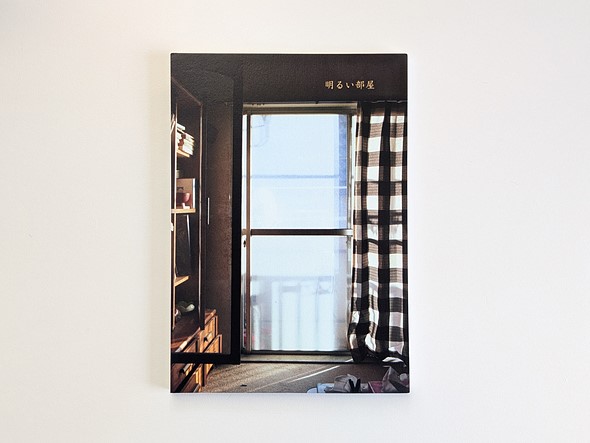a book with a photograph of a window in a house sits on a white desk