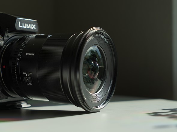 a lens on a camera sits on a white desk in dramatic light