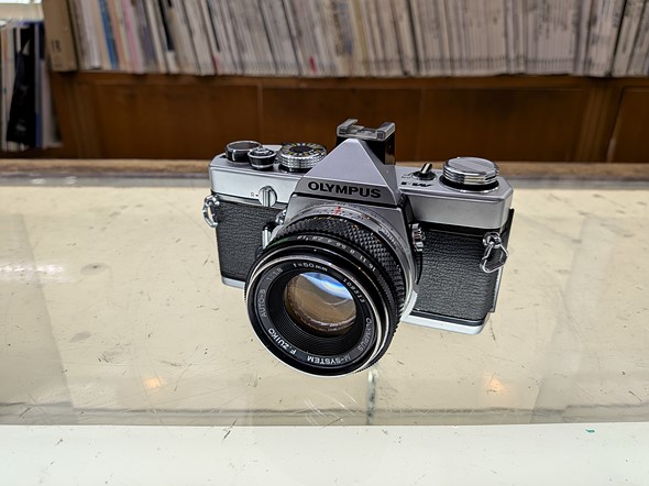 a silver an black slr sits on a marked up glass display case
