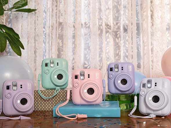 five different colors of instax instant cameras are arranged on a table with confetti and baloons with sheer curtains behind