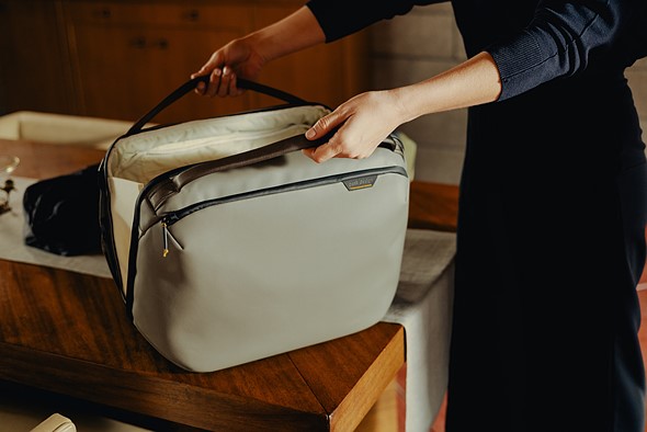 hands open a green bag set on a wood table