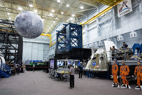 A large Moon model hangs near an Orion capsule in a NASA Artemis facility