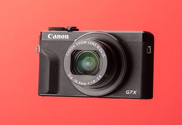 a canon g7x iii compact camera against a red background