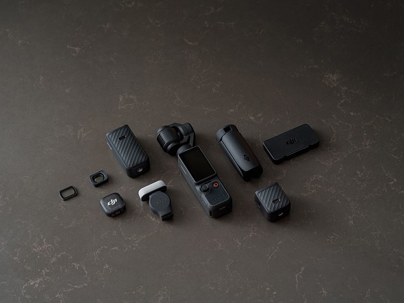 a dji gimbal camera is laid out on a black surface with other vlogging acccessories