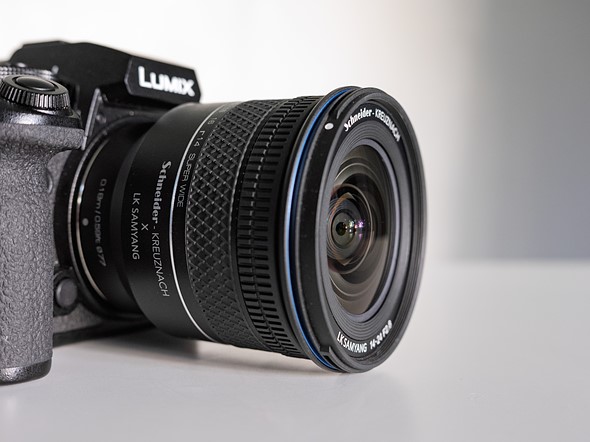 a black camera with lens sits on a white table